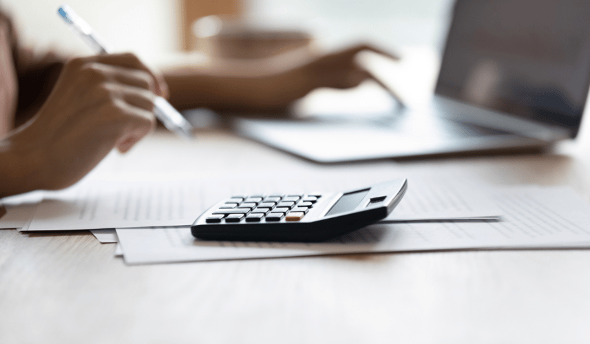 A close-up of a business owner using a calculator and laptop to review credit card processing costs—symbolizing the decision between flat rate pricing and interchange pass-through. Perfect visual for a blog post explaining how each model impacts transparency, cost savings, and compliance.