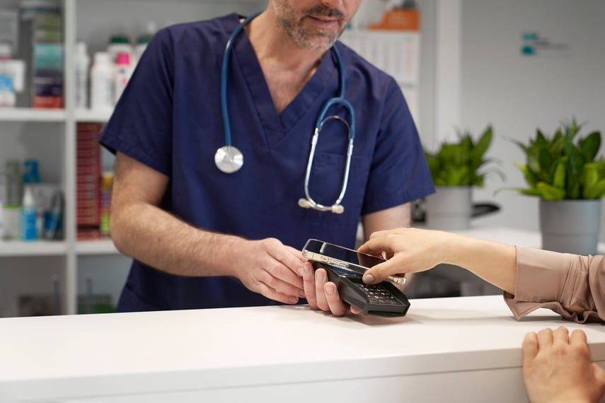 Patient using a smartphone to make a contactless payment at a medical office—illustrating Virtue Payments’ modern, secure, and convenient payment processing solutions tailored for today’s healthcare providers.