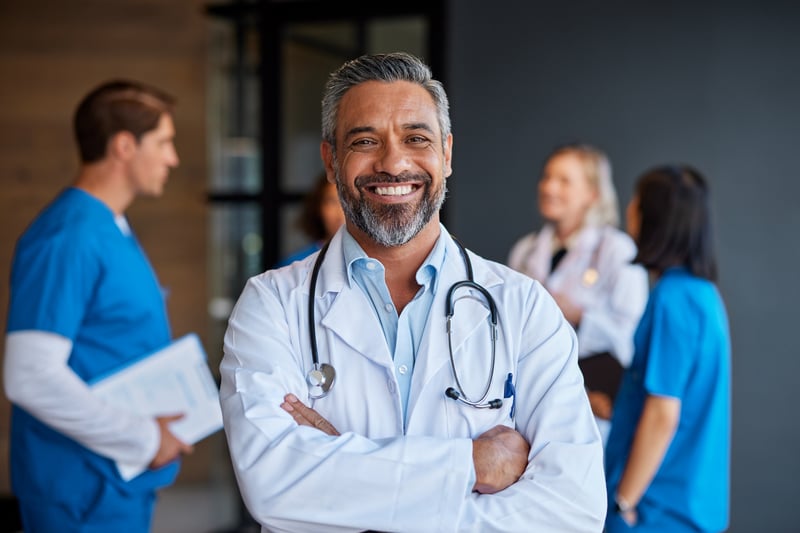 Confident primary care doctor smiling with a team of medical professionals in the background—representing the trust, efficiency, and seamless payment experience Virtue Payments delivers to healthcare practices.