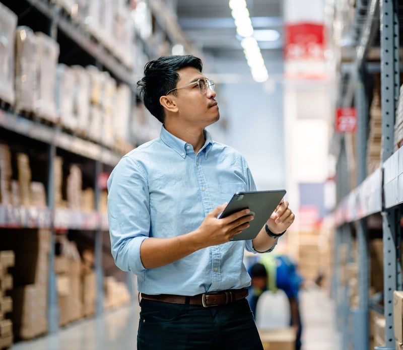Business-to-business B2B owner efficiently operating his business reviewing inventory and payments reporting on tablet in wholesale warehouse benefiting from level 2 & 3 rate savings