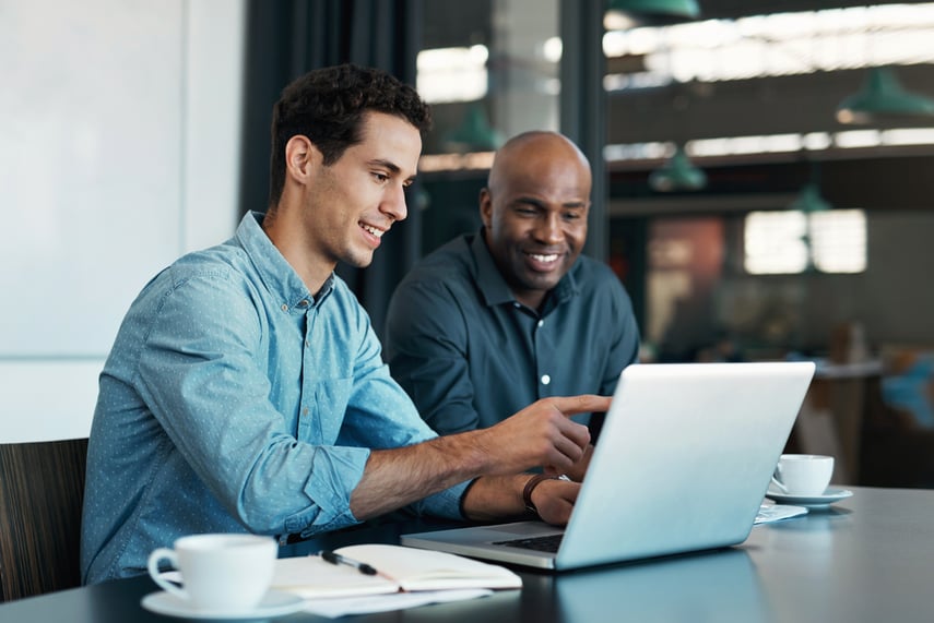 Two professionals collaborating on payment software integration at a laptop, representing technical partnership opportunities with Virtue Payments.