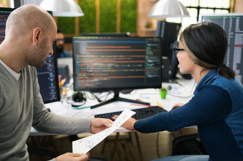 Developers collaborating on payment integration code at a workstation, illustrating technical partnership opportunities with Virtue Payments.