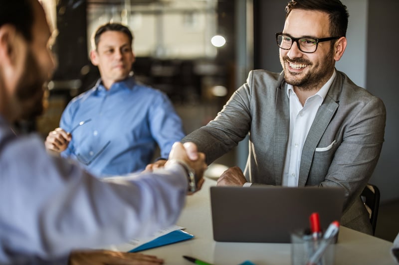 Business professionals finalizing an enterprise partnership with a handshake in a modern office, representing Virtue Payments’ B2B collaboration opportunities.
