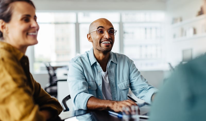 Smiling professional in a casual office setting discussing referral partnership opportunities in fintech and payment solutions.