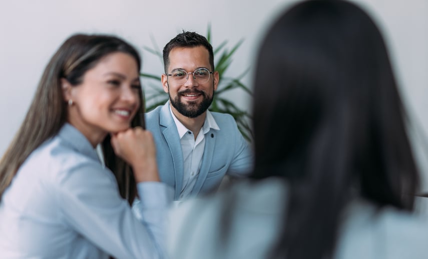Smiling professionals in a business meeting discussing referral partnership opportunities with Virtue Payments in a modern office setting.