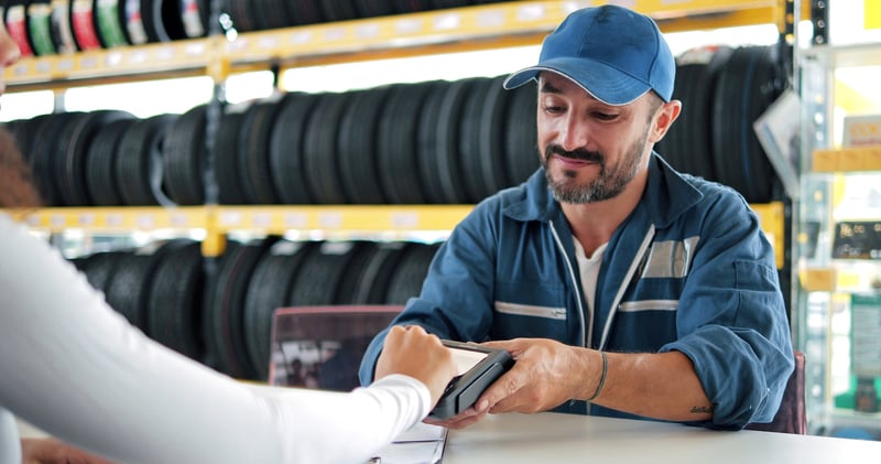 Auto shop technician accepting contactless payment from customer, showing how Virtue Payments supports fast, reliable transactions in service industries