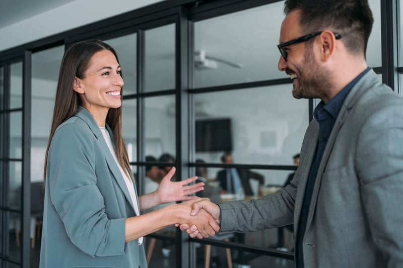 Professional partners shaking hands in modern office, representing business collaboration and trusted relationships through Virtue Payments
